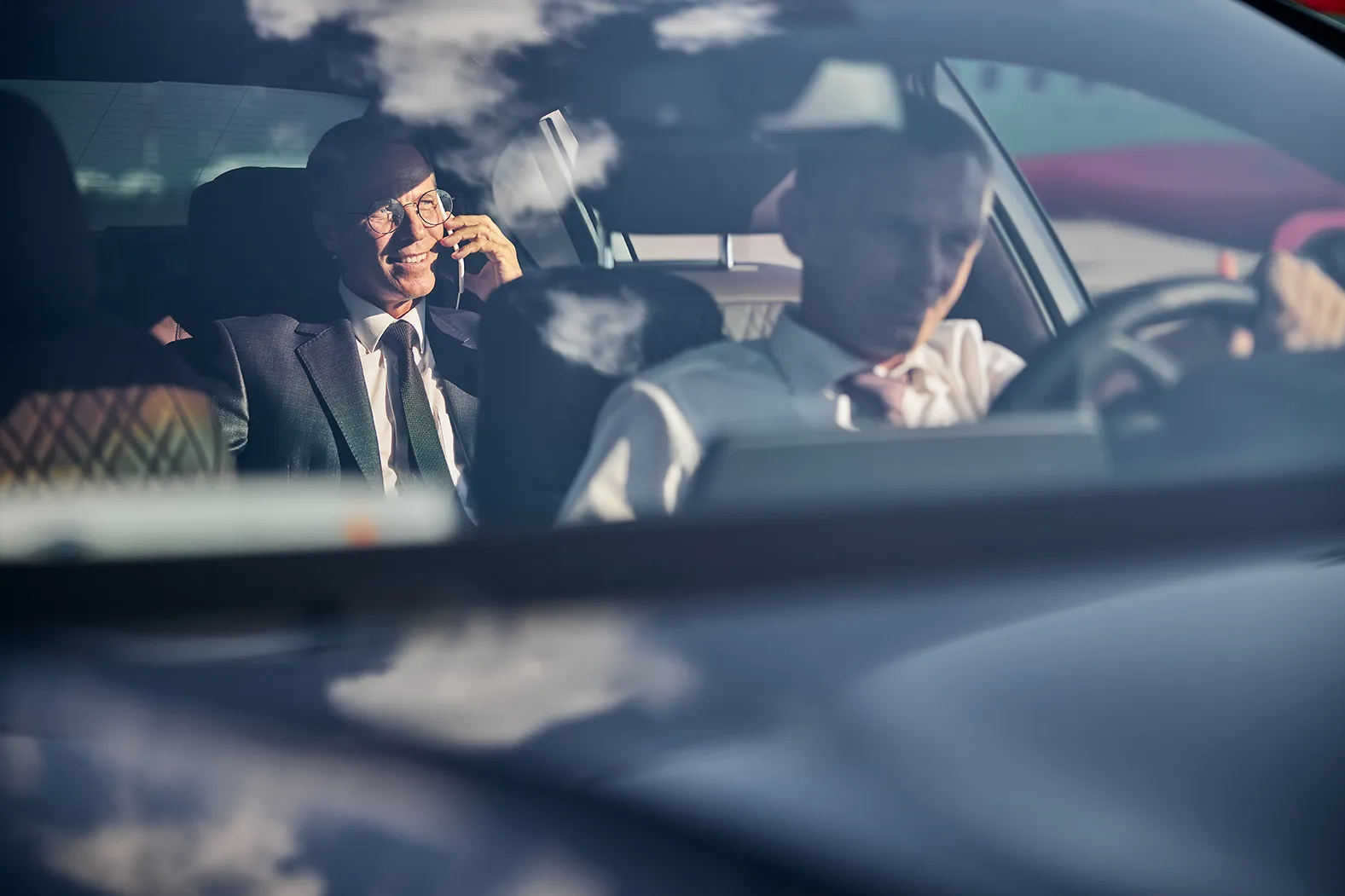 smiling businessman with smartphone travelling with a chauffeur